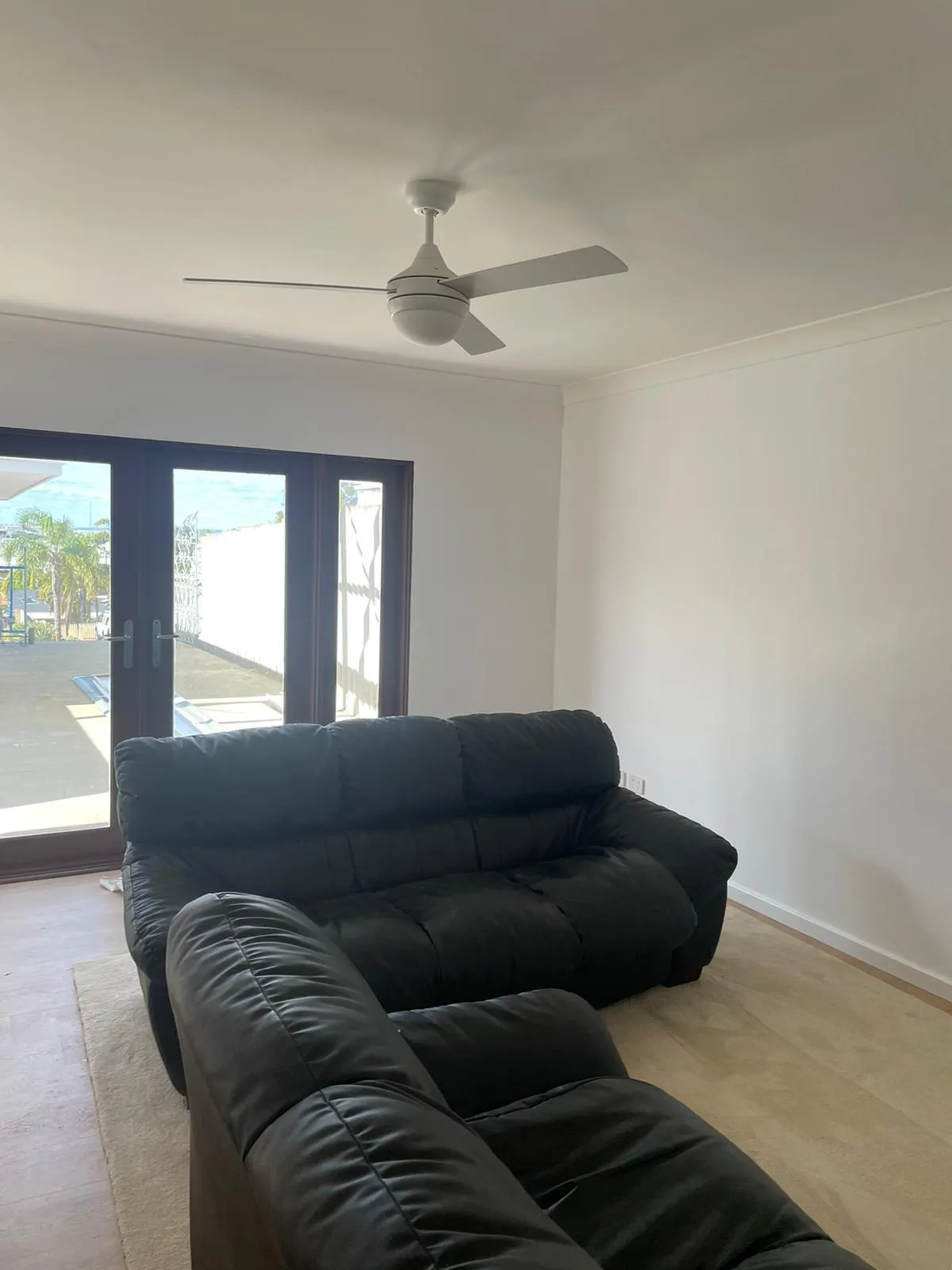 Finished living room with black leather sofas and timber-look flooring