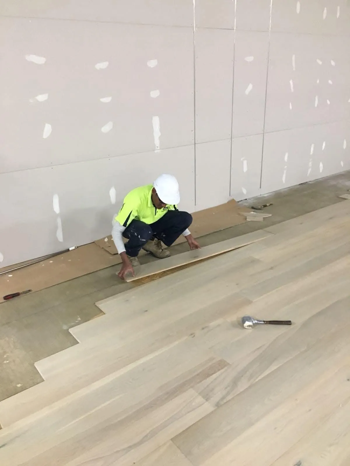 Worker installing timber floorboards